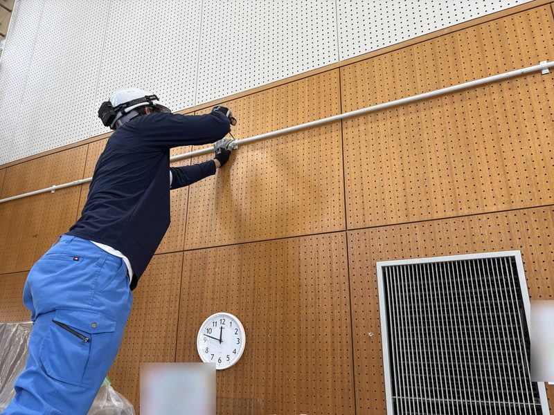 施設の壁に電線管を固定する作業